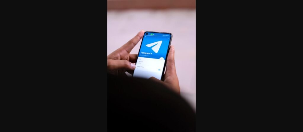 Mão segurando um smartphone com o aplicativo Telegram aberto na tela, ilustrando o uso de links t.me
